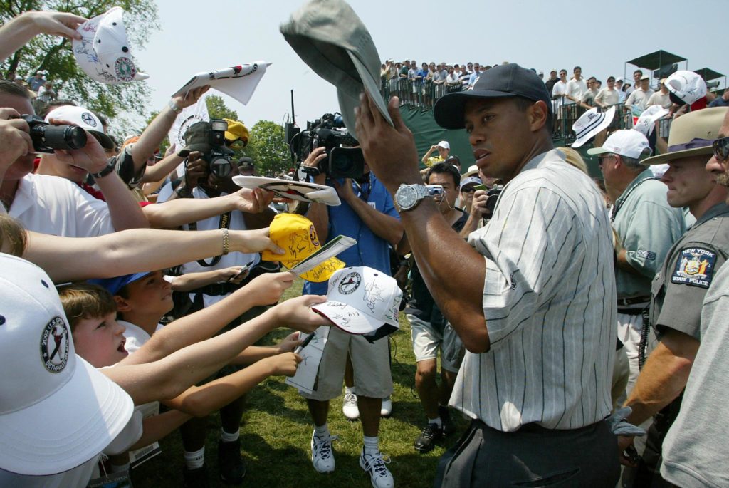 Tiger Woods of the US signs autographs as he walks