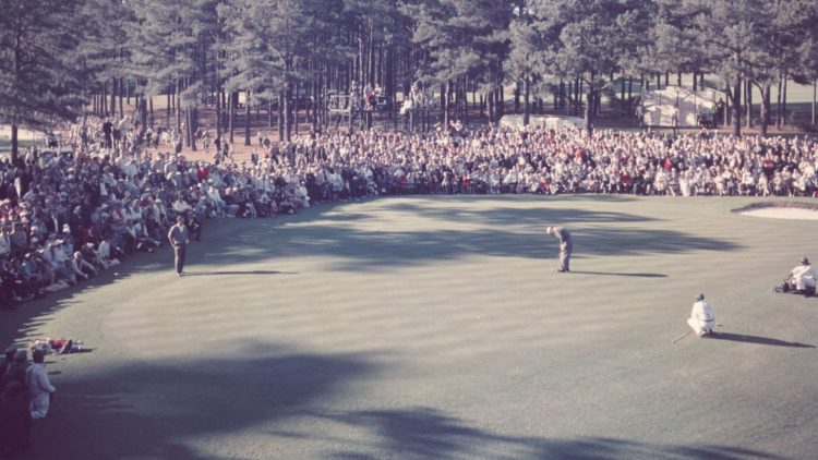 Arnold Palmer watches Charles Coe putt on the 15th hole during the 1961 Masters Tournament at Augusta National Golf Club