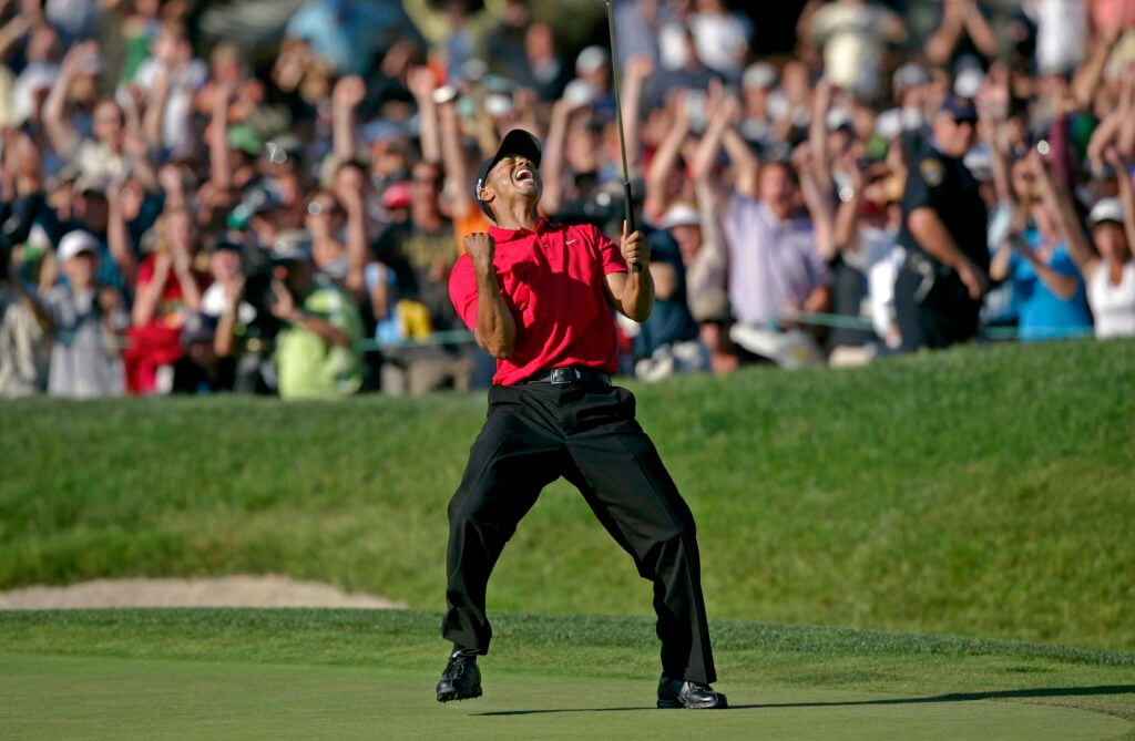Tiger Woods celebrates on the eighteenth green after sinking a putt for a birdie and to force a playoff