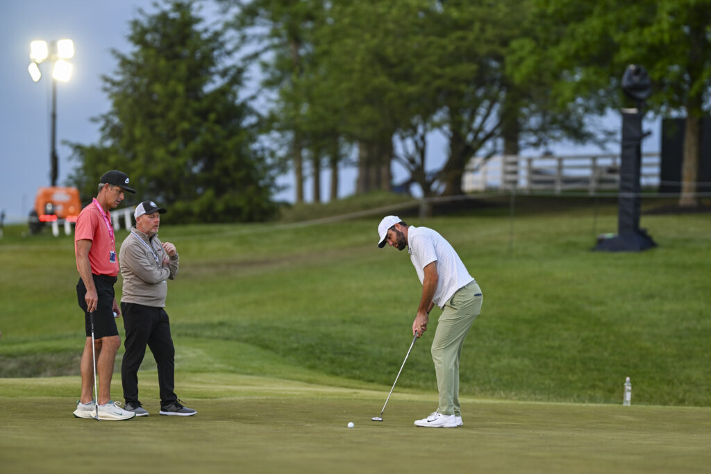 Phil Kenyon and Ted Scott watch Scottie Scheffler practice his putting after round one of the PGA Championship in 2024