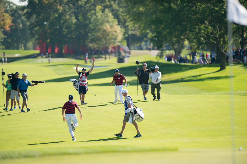 Jordan Spieth runs towards Patrick Reed after Reed made an eagle during the 2016 Ryder Cup