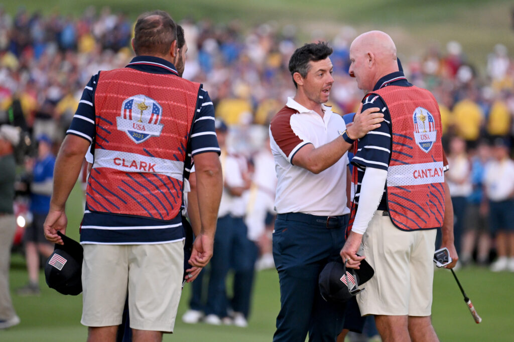 Rory McIlroy of Team Europe speaks with caddie of Patrick Cantlay of Team United States Joe LaCava on the 18th green during the 2023 Ryder Cup