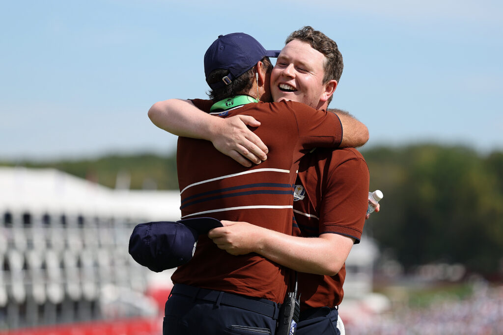 Robert MacIntyre and vice captain Edoardo Molinari of Team Europe embrace at the 2025 Ryder Cup.