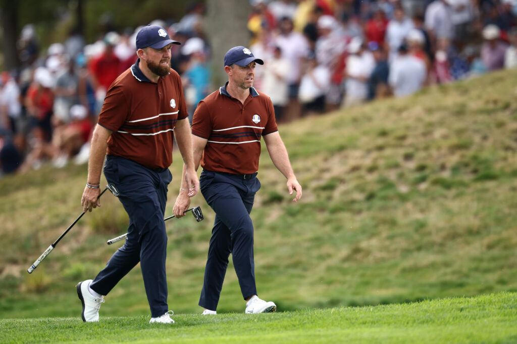 Shane Lowry of Team Europe and teammate Rory McIlroy walk the fifth hole during the Saturday afternoon four-balls matches of the 2025 Ryder Cup
