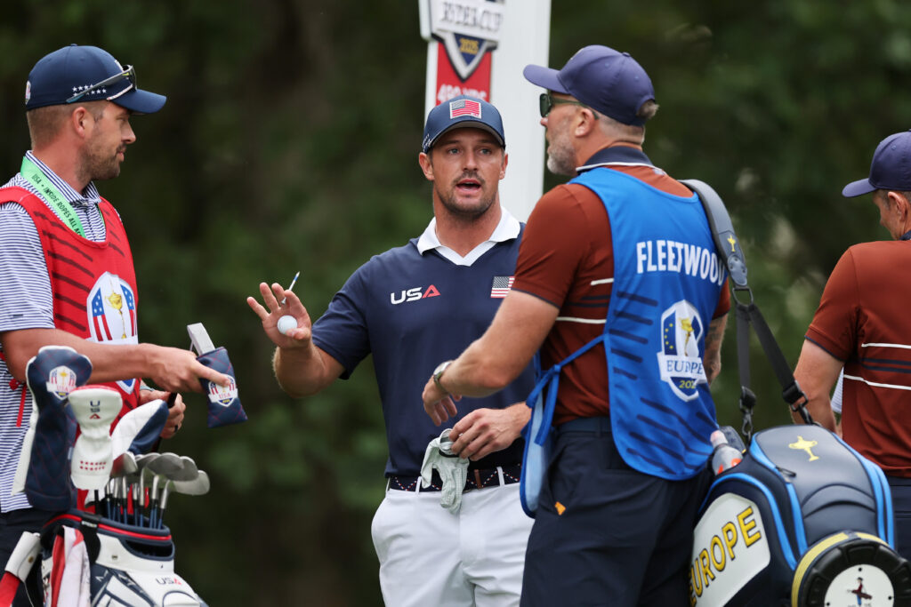 Bryson DeChambeau of Team United States, his caddie Greg Bodine and Ian Finnis, caddie for Tommy Fleetwood of Team Europe exchange words at the 2025 Ryder Cup.