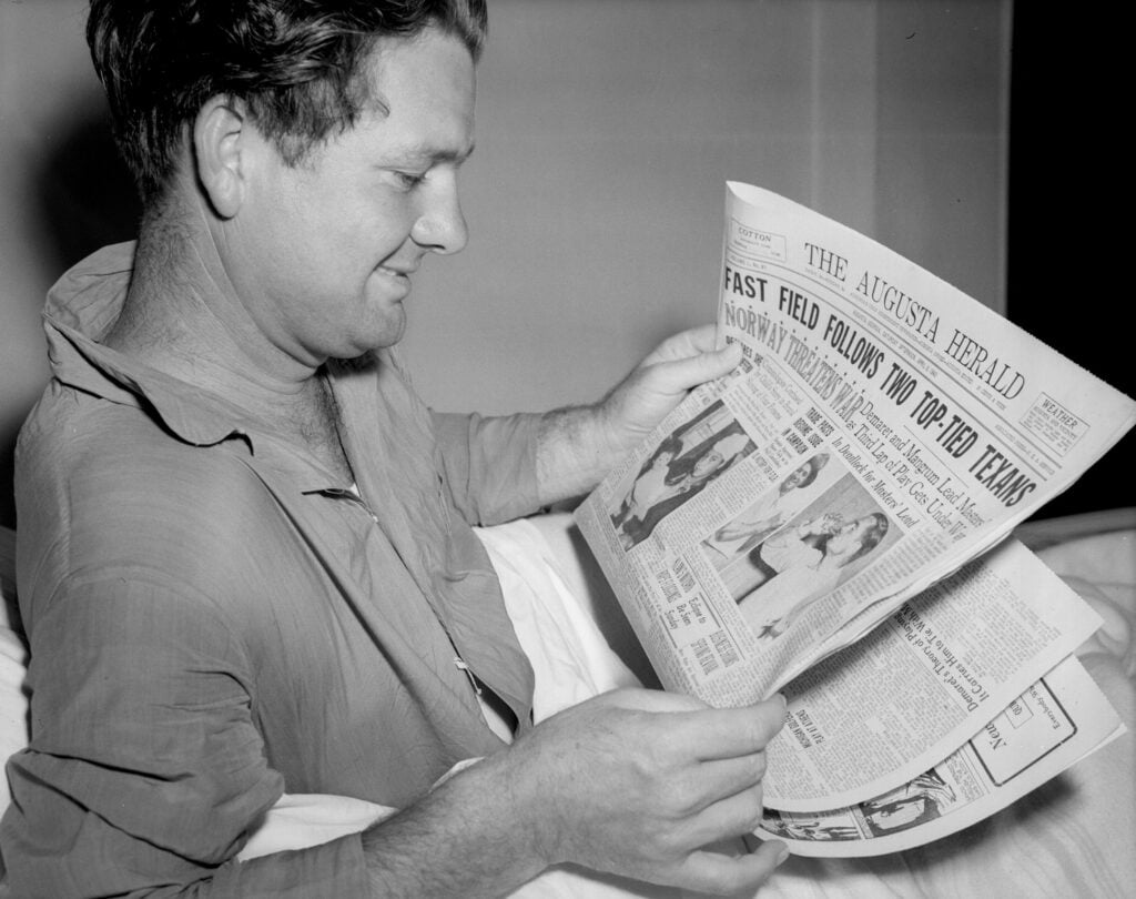 Jimmy Demaret reads headlines about himself and co-leader Lloyd Mangrum while in the hospital after the second round of the 1940 Masters Tournament