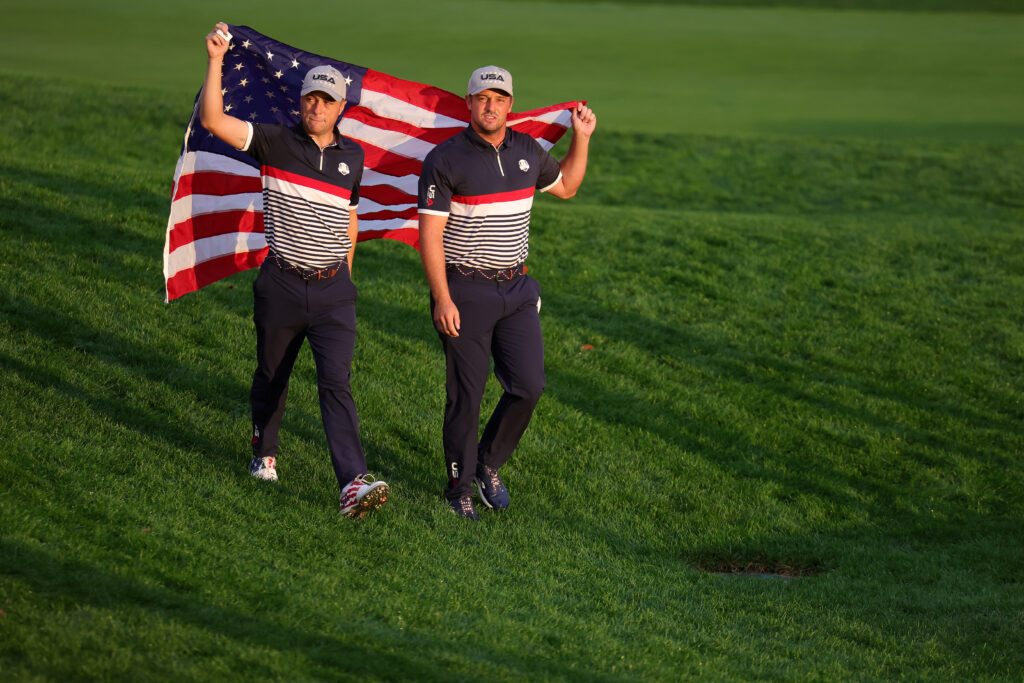 Bryson DeChambeau and Justin Thomas carry the American flag during the Ryder Cup in 2025