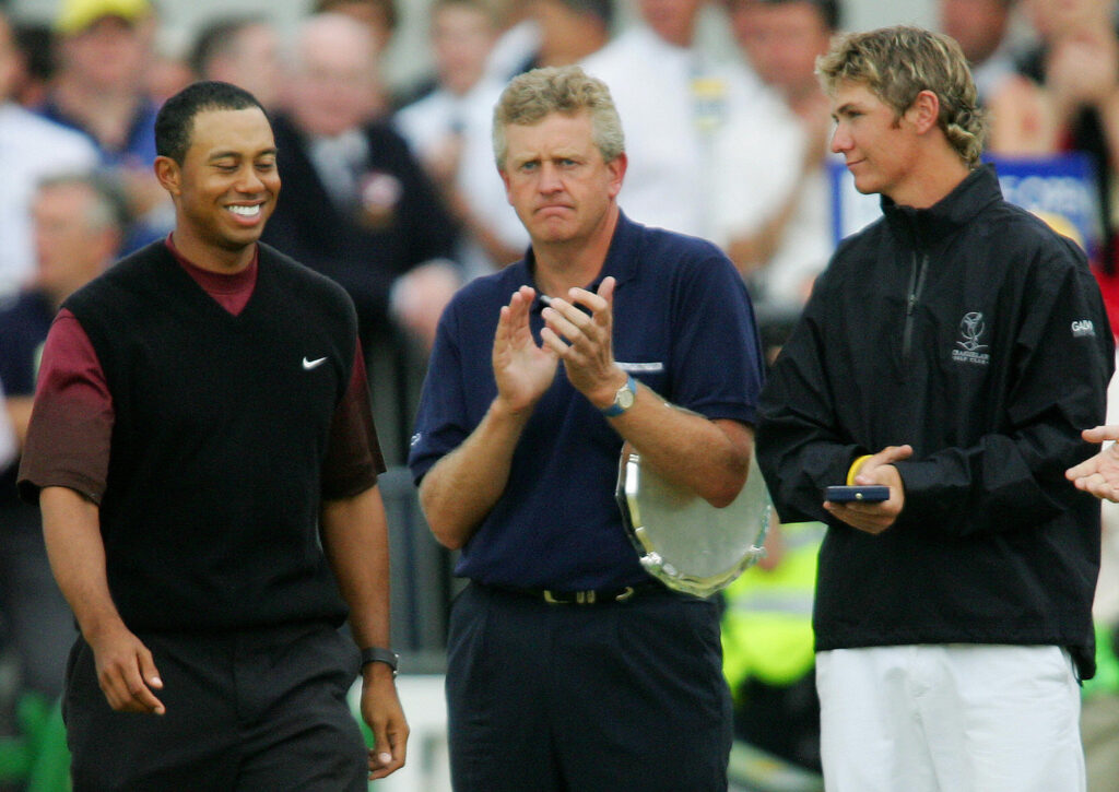 Tiger Woods (L) of the US walks past runner up Colin Montgomerie of Scotland and amatuer winner Lloyd Saltman (R) of Scotland to collect the Claret Jug at the 134th Open Championship