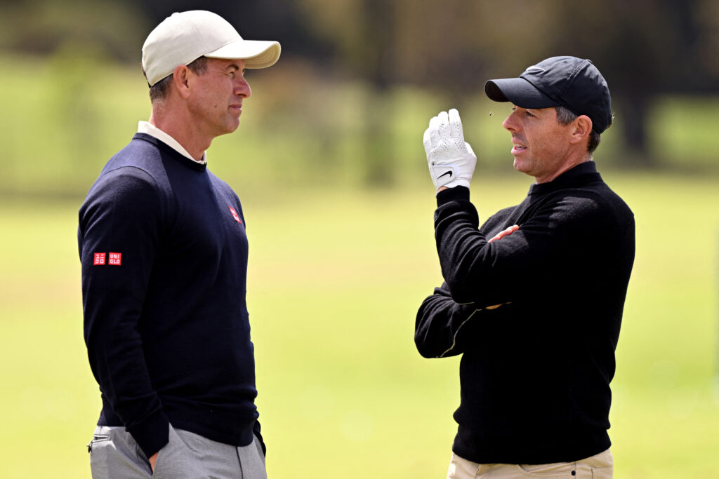 Rory McIlroy (R) talks to Adam Scott before a practice round for the Australian Open golf tournament at the Royal Melbourne Golf Club