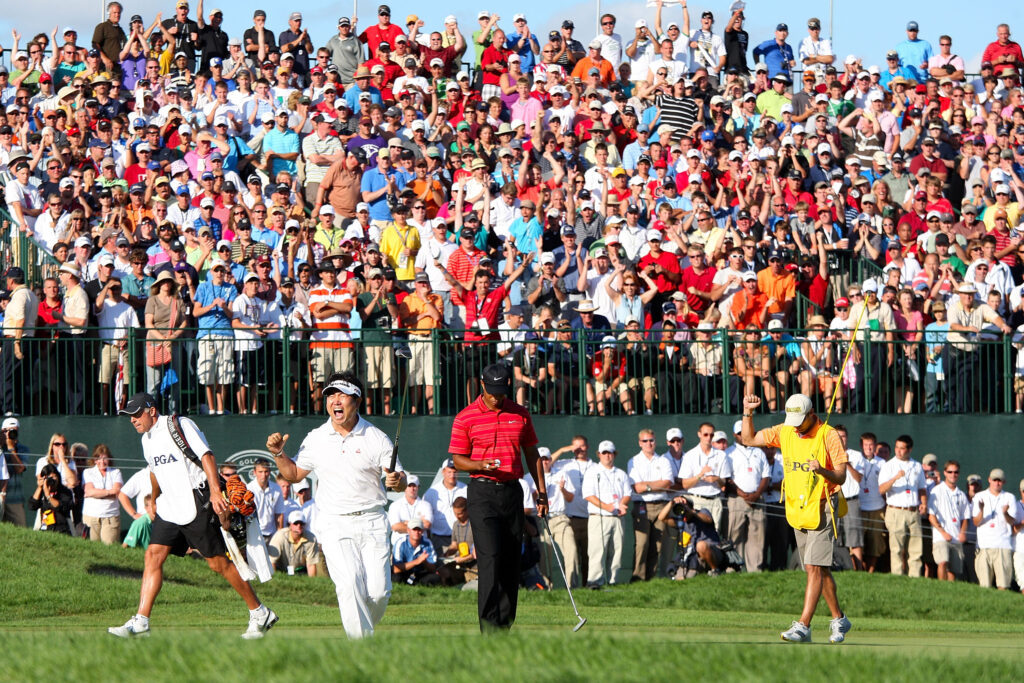 Y.E. Yang of South Korea celebrates a birdie putt on the 18th green alongside Tiger Woods during the final round of the 91st PGA Championship at Hazeltine National Golf Club