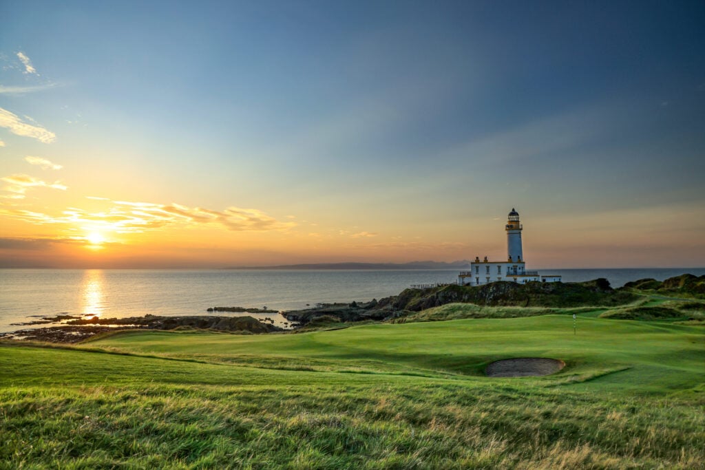 A view at sunset of the green on the par 3, ninth hole with the lighthouse on The Ailsa Course at The Trump Turnberry