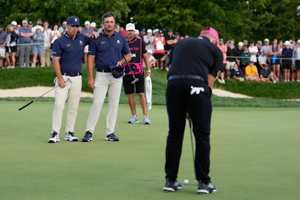 Paul Casey and Bryson DeChambeau look on as Tyrrell Hatton makes a putt to win the LIV Golf Team Championship